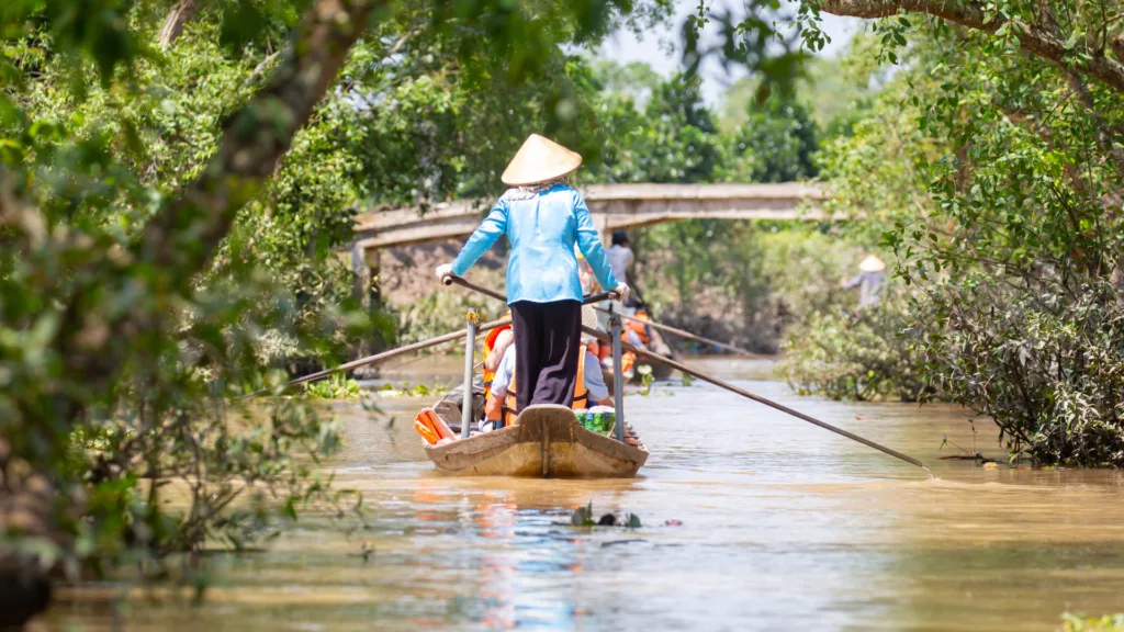 Barca de remo recorriendo un canal del delta del Mekong, Vietnam